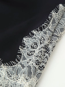 Détail du tissu d'une robe noire avec bordure en dentelle de cils blanche raffinée