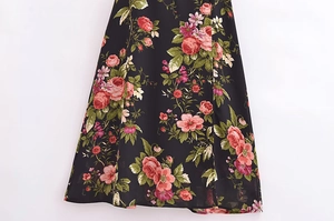 Detail view of floral print on black chiffon dress showing red roses and slit hemline
