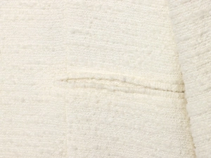 Detailed macro view of cream-colored tweed fabric texture and flat stitched welt pocket