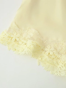 Détail de l'ourlet du caraco jaune pâle avec broderie de dentelle florale délicate
