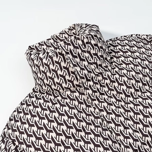 Close-up of winter puffer jacket featuring high collar and brown monogram pattern detail