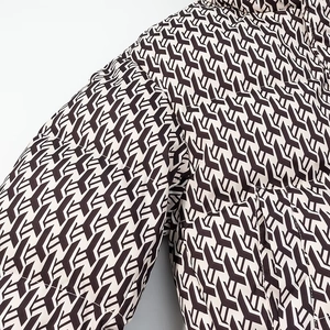 Detailed close-up of quilted winter jacket with geometric monogram pattern and padded texture