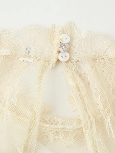 Détail de la dentelle avec ouverture goutte d'eau et boutons en perles blanches sur robe