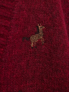Detailed view of burgundy mohair knit fabric with handmade beaded animal embroidery