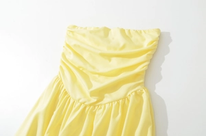 Close-up of ruched strapless dress bodice in light lemon yellow synthetic fabric