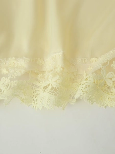 Détail de la bordure en dentelle florale sur débardeur en satin crème et short