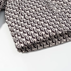 Detailed view of quilted winter jacket fabric with brown geometric Y-pattern print
