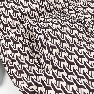 Detailed macro view of quilted winter jacket fabric with brown geometric patterns