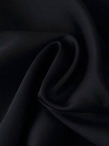 Détail de la texture d'un tissu noir lisse avec un lustre soyeux et un beau drapé