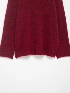 Close-up of wine red knit cardigan featuring soft plush texture and ribbed hem detail