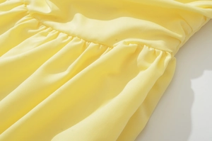 Detail of yellow dress showing high-quality stitching and elegant ruching textures