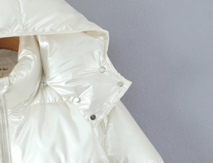 Detailed shot of pearly white puffer jacket hood with metallic snap buttons and silver zipper