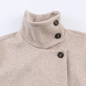 Détail du col montant et des boutons marron sur le manteau en laine beige