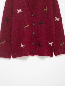 Detail of burgundy knit cardigan featuring colorful mini horse embroidery and black buttons