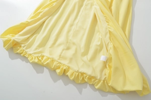 Detailed macro view of yellow dress fabric featuring ruffle hem and garment care label