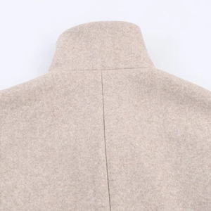 Gros plan détaillé du col montant et de la couture centrale du manteau en laine beige