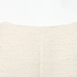 Close-up of white tweed jacket showing intricate woven texture and round neckline