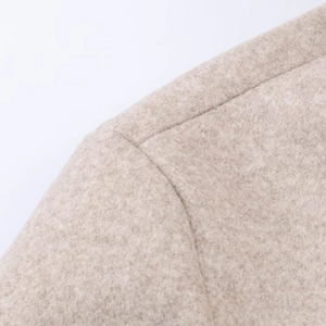 Gros plan sur la couture de l'épaule et la texture du manteau en laine beige clair