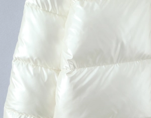 Detailed close-up of shiny white quilted winter puffer jacket with horizontal stitching