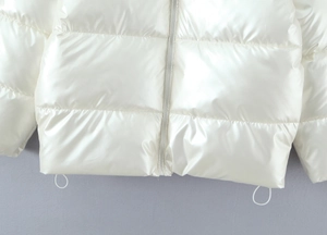 Detail of white glossy puffer jacket featuring silver zipper and elastic hem drawstrings