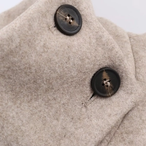 Vue macro des boutons à motif marbré sur le tissu d'un manteau en laine beige