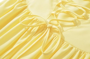 Detailed view of the lace-up back design and pleated fabric on a pale yellow dress