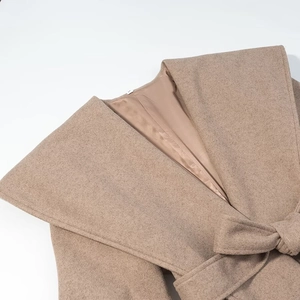 Détail de la texture du manteau en laine avec grand revers et ceinture assortie