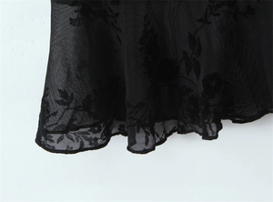 Detail of black mesh fabric with floral embroidery and neat overlock stitching on the hem