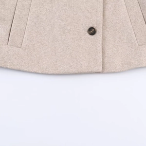 Gros plan sur le tissu du manteau en laine beige avec bouton écaille et poche