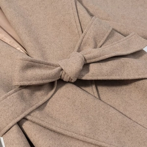 Détail de la ceinture et texture laineuse sur ce manteau long pour femme en camel