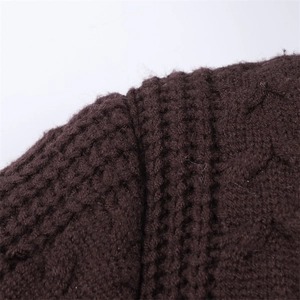 Macro shot of dark brown knitted sweater showing thick braided texture and shoulder stitching
