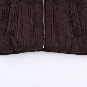Detail of chunky knit winter jacket featuring cable pattern and gold metal zipper