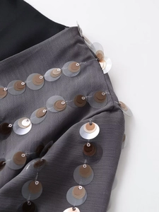 Detailed close-up of multi-layer metallic sequins on grey textured long sleeve bodysuit