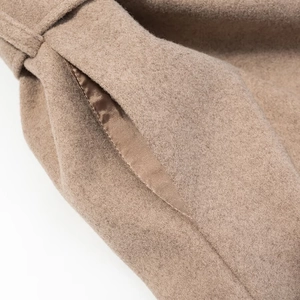 Gros plan détaillé des coutures de poche et de la doublure en satin d'un manteau camel