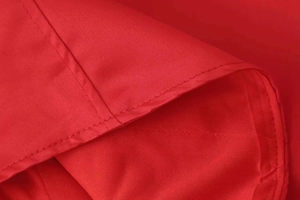 Detaillierte Makroansicht der Doppelnaht und Stofftextur an einem roten Sommerkleid