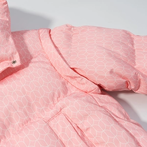 Détail du tissu matelassé rose avec motif géométrique et bouton-pression en métal argenté