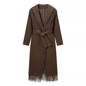 Detail of a brown wool coat featuring long fringe trim, a wide hood, and a waist tie belt