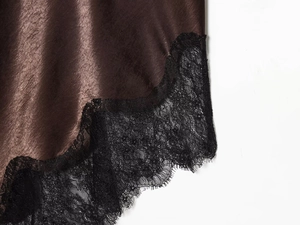Detailed macro view of chocolate brown satin hem with black eyelash lace trim