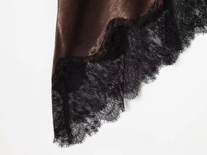 Detailed macro view of chocolate satin fabric hem with intricate black eyelash lace edge