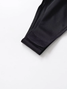 Detail of the snap button crotch closure on a black long sleeve sequin bodysuit