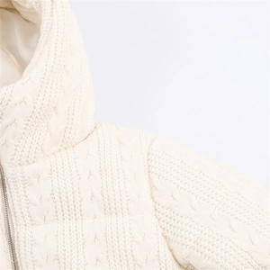 Detailed close-up of cream cable knit texture and metal zipper on hooded jacket