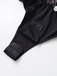 Detail view of adjustable snap button closure on the crotch of a black long sleeve bodysuit