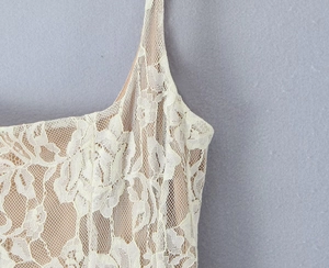Close-up of floral lace texture with nude lining on ivory slim strap dress