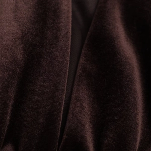 Détail de la texture du tissu en velours marron foncé avec un fini brillant et des coutures