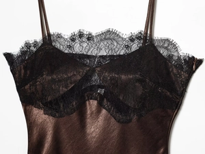 Detailed view of dark brown satin dress featuring delicate black lace trim and side zipper