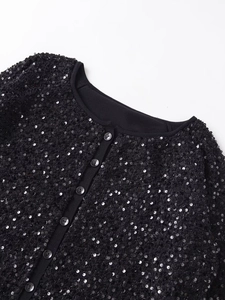 Detailed view of the black sequined jacket showing the round neck and dark button closure