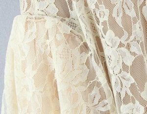 Close-up of fine floral lace embroidery on cream slim-fit dress with mesh texture