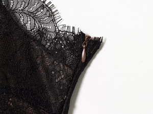 Close-up of black lace dress showing delicate eyelash trim and hidden zipper detail