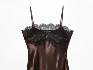 Close-up of brown satin dress featuring delicate black lace trim and fine straps