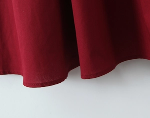 Vue macro détaillée de l'ourlet de la robe rouge foncé avec finitions de couture de qualité